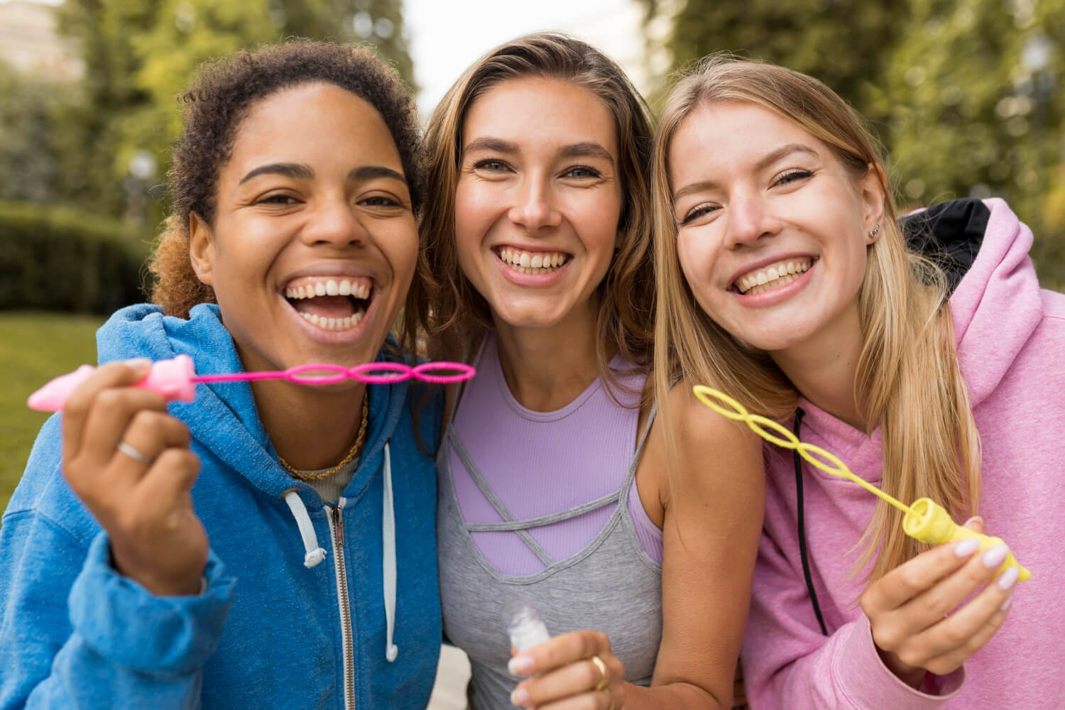 Três adolescentes sorrindo com dentes alinhados ao ar livre, representando o sucesso do tratamento com alinhadores na Aliança Clínica em Nossa Sra da Glória.